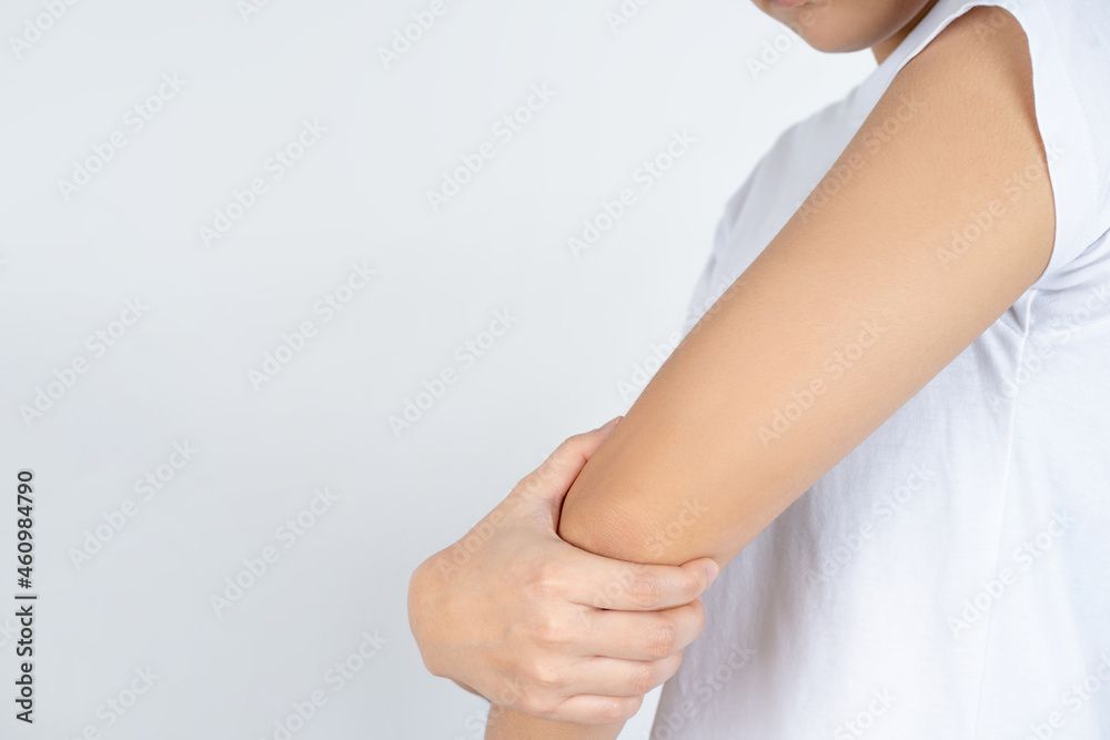 Woman feeling a pain in his elbow on grey background. She has suffering