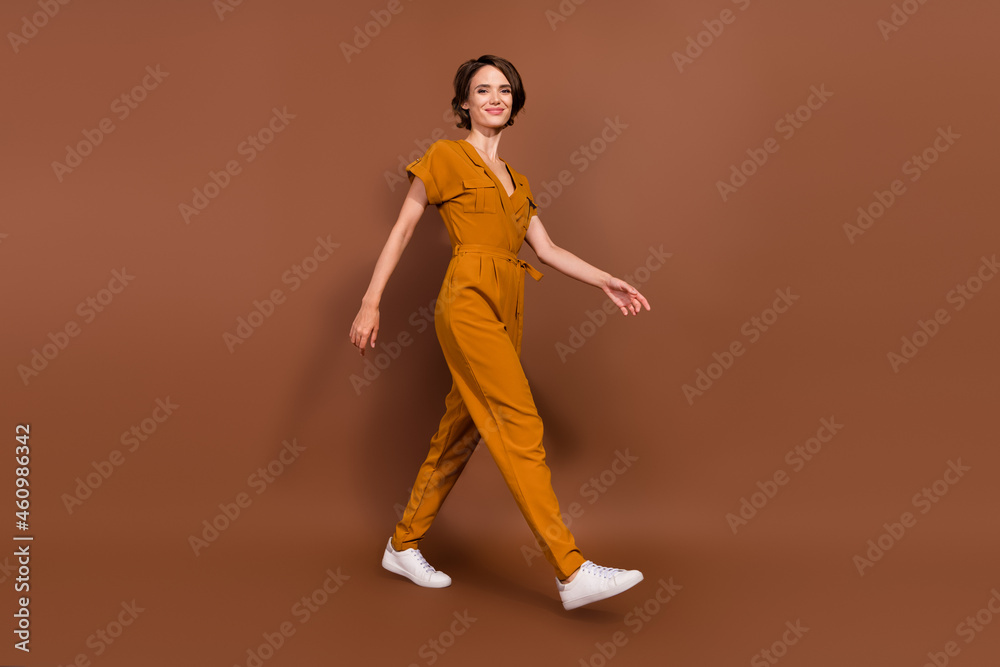 Full size photo of cheerful positive young woman walk weekend empty space enjoy isolated on brown color background Full size photo of cheerful positive young woman walk weekend empty space enjoy isolated on brown color background
