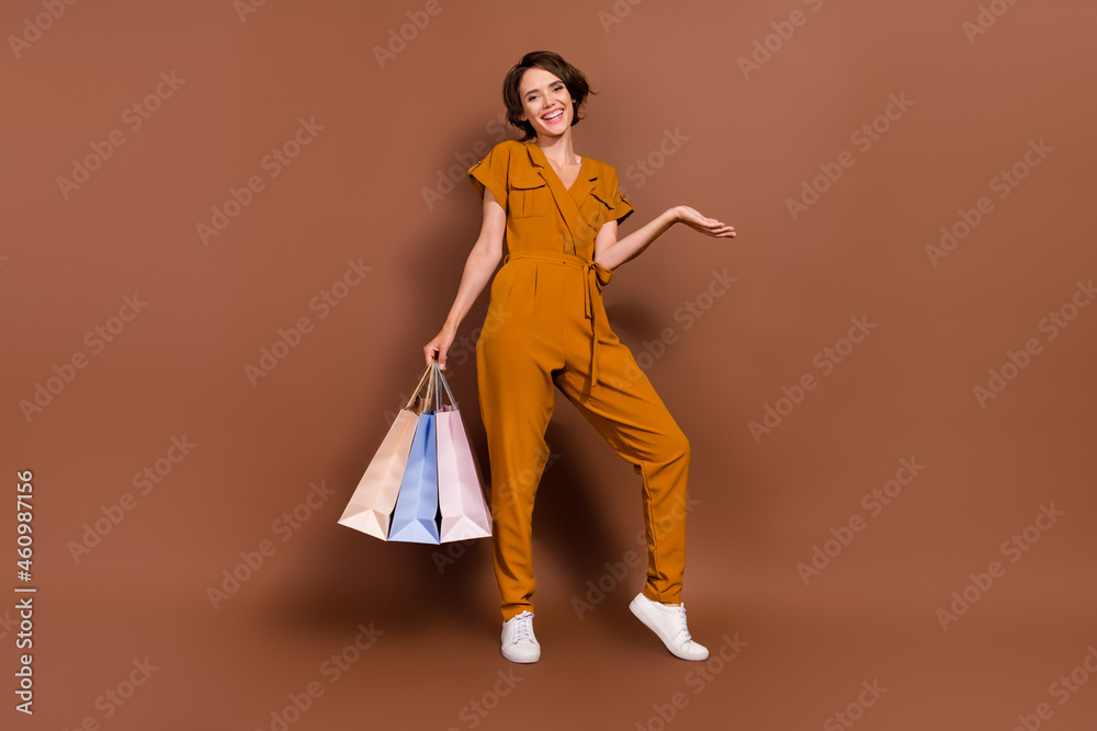 Full body photo of attractive cool happy young woman hold hands many bags sale isolated on brown color background Full body photo of attractive cool happy young woman hold hands many bags sale isolated on brown color background