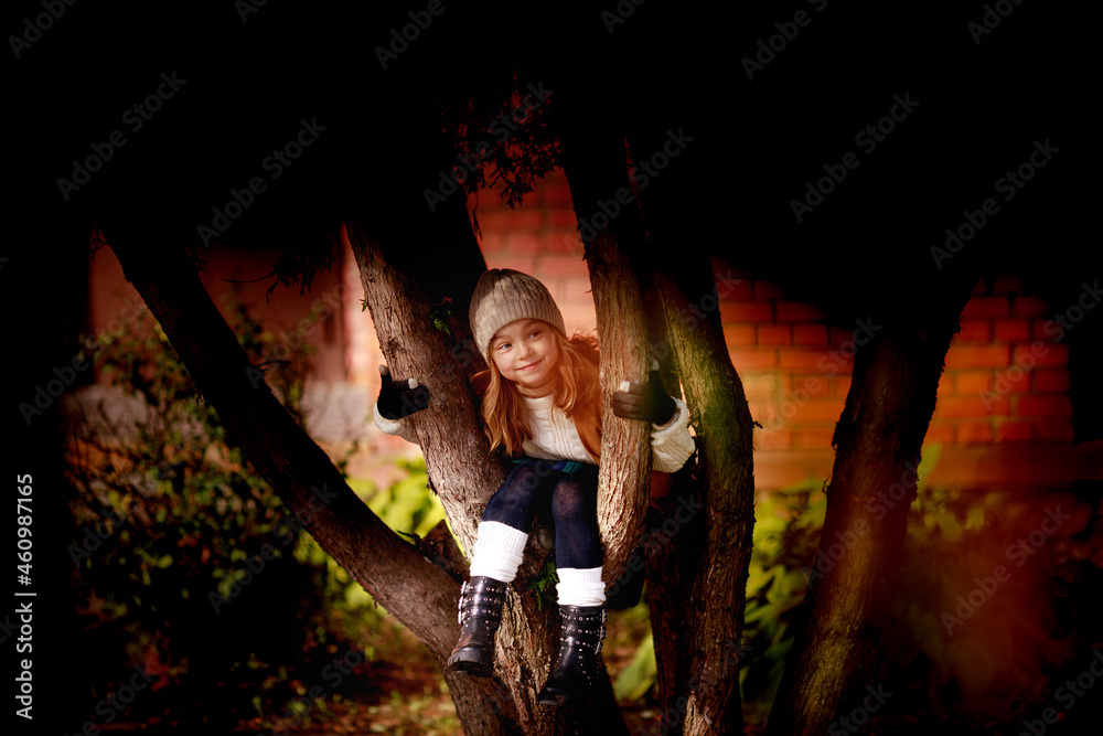 Obraz premium dressed in autumn clothes cute girl sitting on a tree
