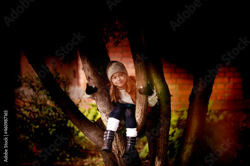 dressed in autumn clothes cute girl sitting on a tree