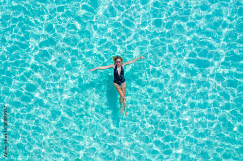 Top view aerial of a seductive sexy model in black swimwear is enjoying relax in turquoise sea summer weekend. Tropical background with empty space. © Timelapse4K