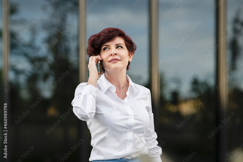 Beautiful female professional talking on mobile phone outside office building Beautiful female professional talking on mobile phone outside office building