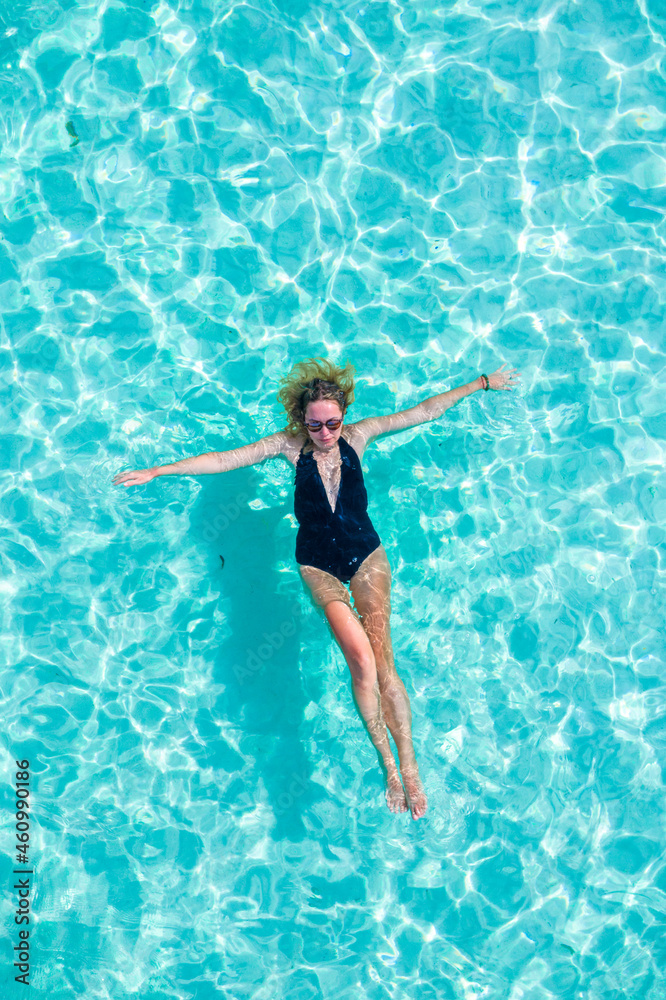 Top view aerial of a seductive sexy model in black swimwear is enjoying relax in turquoise sea summer weekend. Tropical background with empty space.