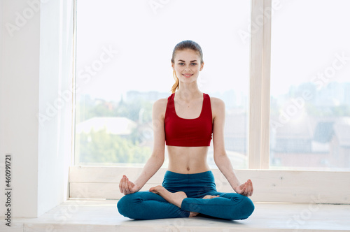 sportive woman doing yoga exercise asana near the window