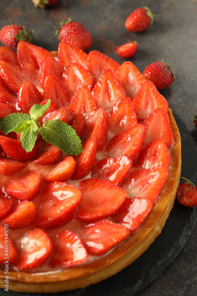 Tray with strawberry tart on dark textured table