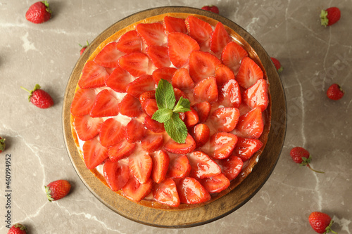 Wooden stand with strawberry tart on gray textured background