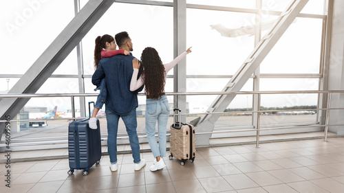 Family Travel. Parents With Little Daughter Standing At Airport Terminal, Rear View