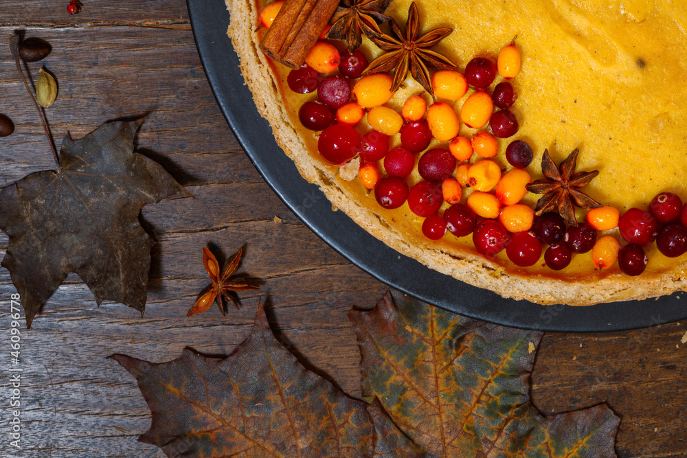 Pumpkin cheesecake with berries, close-up. On a rough wooden background with dark autumn leaves. Pumpkin cheesecake with berries, close-up. On a rough wooden background with dark autumn leaves.