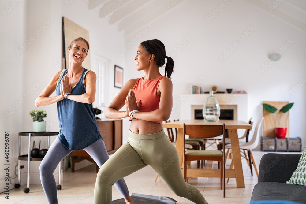 Fototapeta premium Happy mature women friends practicing yoga at home