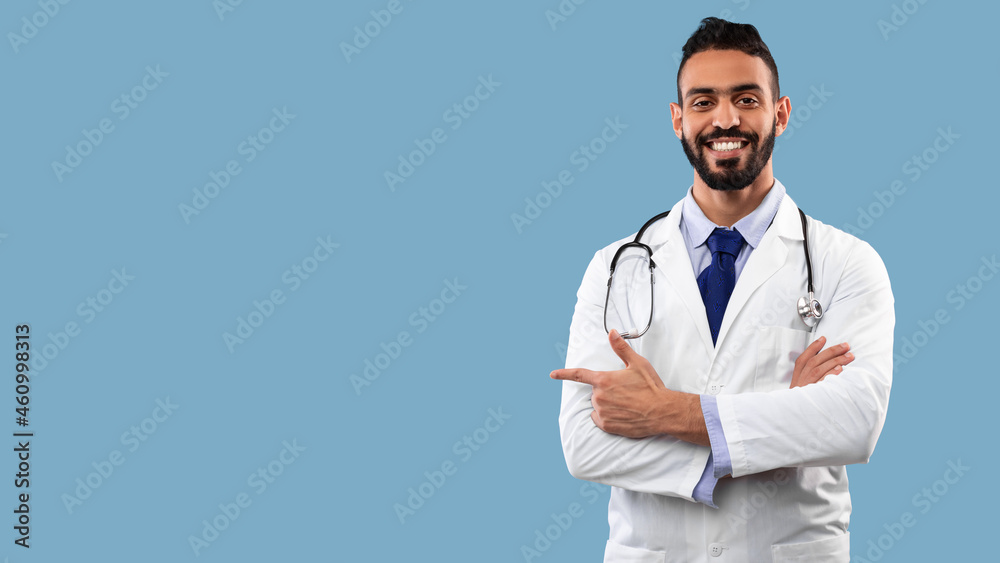 Middle-Eastern Male Doctor Pointing Finger Aside At Copyspace, Studio Shot Middle-Eastern Male Doctor Pointing Finger Aside At Copyspace, Studio Shot