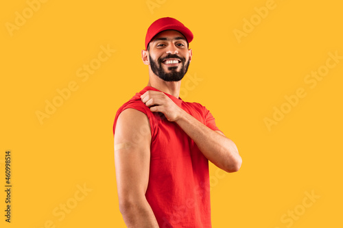 Vaccinated Arabic Courier Man Showing Arm After Vaccination, Yellow Background