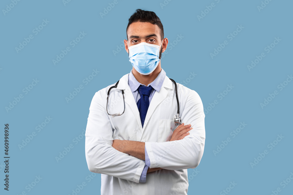 Portrait Of Arab Male Doctor Wearing Face Mask, Blue Background Portrait Of Arab Male Doctor Wearing Face Mask, Blue Background