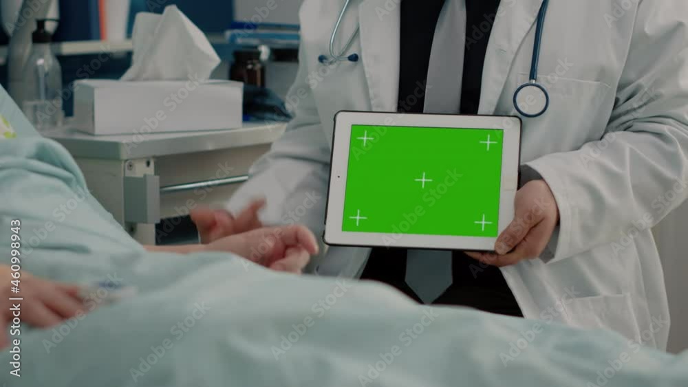 Close up of horizontal green screen on tablet in hand of doctor at nursing home facility. Medic pointing at chroma key on gadget with mockup template and isolated background for patient Close up of horizontal green screen on tablet in hand of doctor at nursing home facility. Medic pointing at chroma key on gadget with mockup template and isolated background for patient