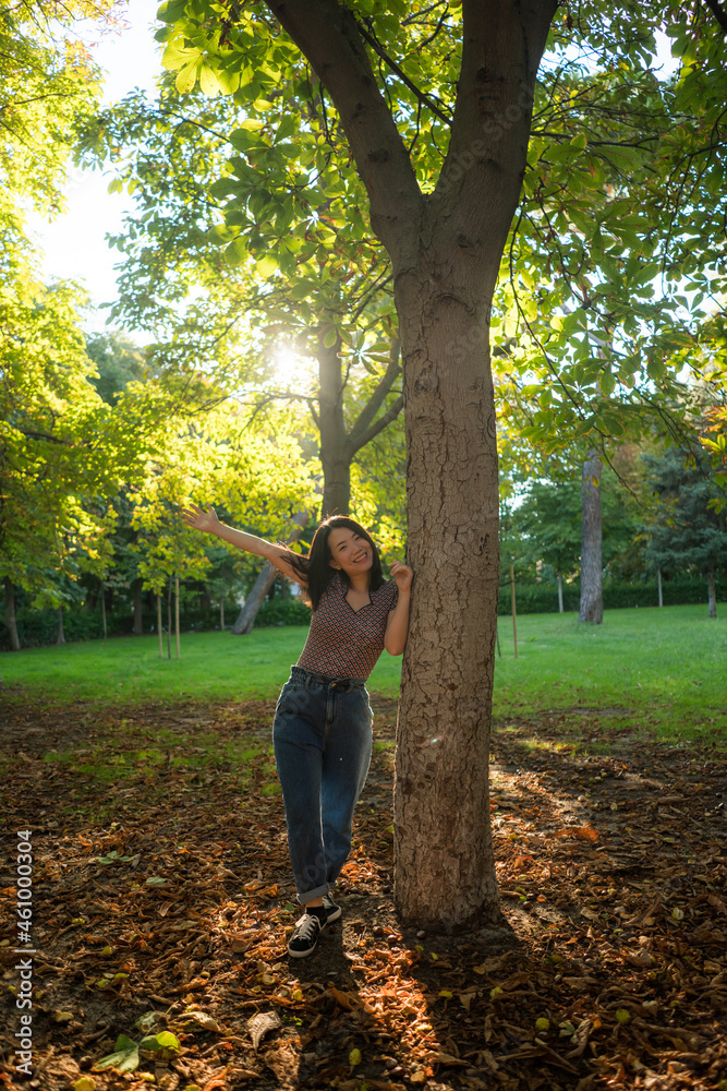 vertical outdoors lifestyle portrait of young happy and beautiful Asian Korean woman enjoying relaxed and cheerful at city park in Autumn full of tree leaves on the ground vertical outdoors lifestyle portrait of young happy and beautiful Asian Korean woman enjoying relaxed and cheerful at city park in Autumn full of tree leaves on the ground