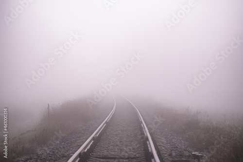 Railroad track in a thick white fog, forest in the background. Concept landscape. Sorrow, loneliness, impasse. Defocused
