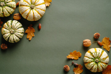 Happy Thanksgiving day concept. Autumn composition with ripe pumpkins, fallen leaves, walnuts, acorns on vintage green background. Flat lay, top view, copy space.