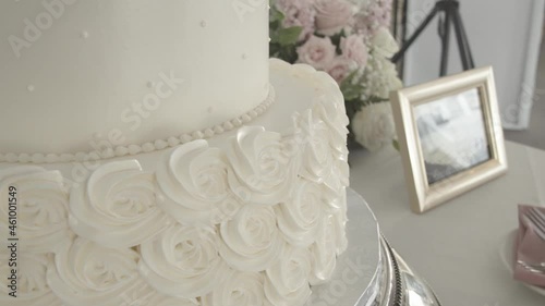 Close-up of the base of the wedding cake in a detail of roses. White backing table, side view with shadows of passers-by. St Benicia. California photo