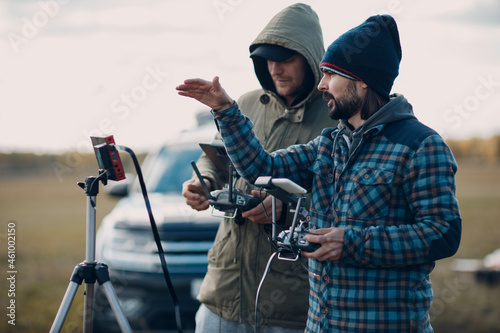 Man pilot controlling quadcopter drone with remote controller pad.