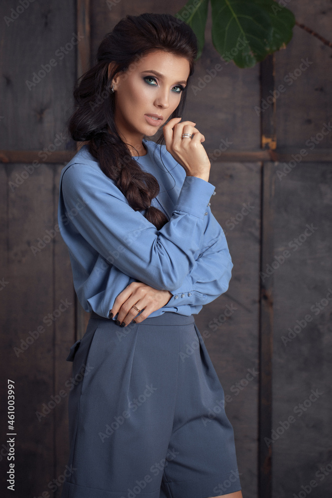 Studio portrait of self confident young female fashion model with long hair in trendy business clothes in blue tones. Collection of comfortable business clothes.