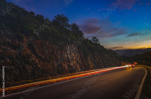 night mountain road with car lights trail