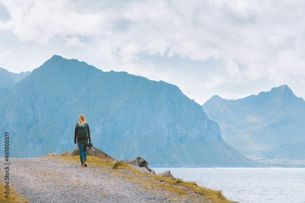 Woman hiking in Norway traveling solo with backpack vacations outdoor active healthy lifestyle explore Lofoten islands