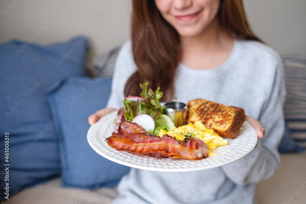 A young woman holding and showing an American breakfast dish at home A young woman holding and showing an American breakfast dish at home