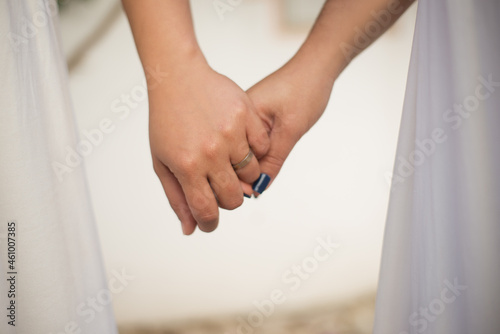 Close-up of women holding hands. Two females in wedding dresses. Golden engagement ring. Wedding, LGBT, celebration concept