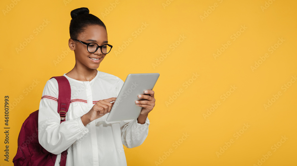 Cheerful smart teen afro american girl pupil in glasses with backpack studying with digital tablet, prepare to exam Cheerful smart teen afro american girl pupil in glasses with backpack studying with digital tablet, prepare to exam