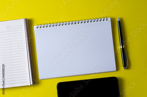 Top view of blank open notebook on yellow background and different objects. Minimal flat lay style.