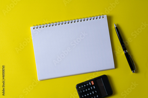 Top view of blank open notebook on yellow background and different objects. Minimal flat lay style.