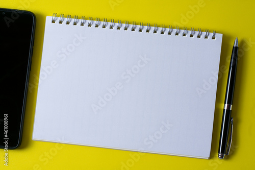 Top view of blank open notebook on yellow background and different objects. Minimal flat lay style.