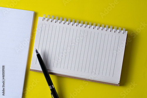 Top view of blank open notebook on yellow background and different objects. Minimal flat lay style.