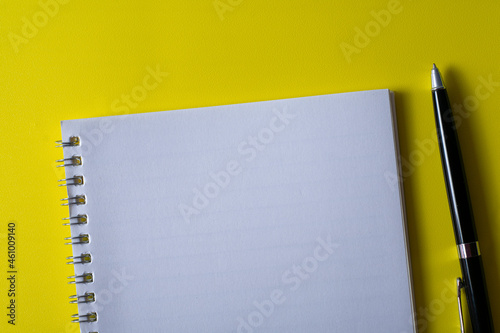 Top view of blank open notebook on yellow background and different objects. Minimal flat lay style.