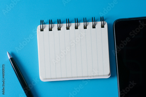 Top view of blank open notebook on blue background and different objects. Minimal flat lay style.