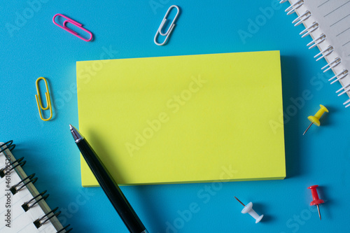 Top view of blank sticky notes on blue background and different objects. Minimal flat lay style.