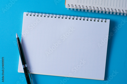 Top view of blank open notebook on blue background and different objects. Minimal flat lay style.