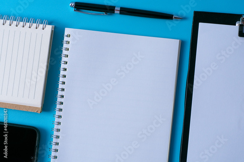 Top view of blank open notebook on blue background and different objects. Minimal flat lay style.