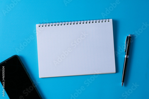 Top view of blank open notebook on blue background and different objects. Minimal flat lay style.