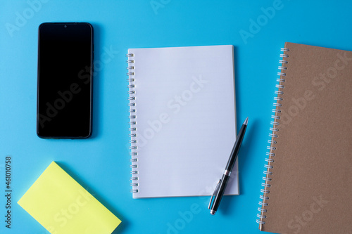 Top view of blank open notebook on blue background and different objects. Minimal flat lay style.