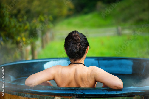 Young woman in an open-air bath with a view of the mountains.