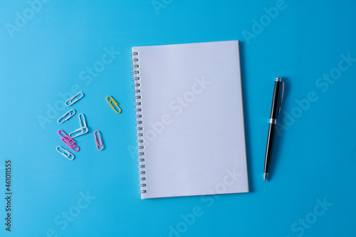 Top view of blank open notebook on blue background and different objects. Minimal flat lay style.