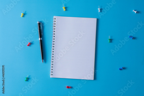 Top view of blank open notebook on blue background and different objects. Minimal flat lay style.
