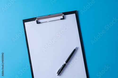 Top view of blank paper on clipboard on blue background and different objects. Minimal flat lay style.