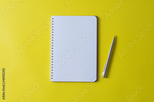 Top view of blank open notebook on yellow background and different objects. Minimal flat lay style.