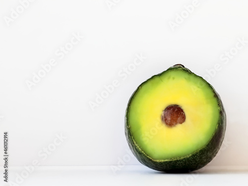 Half an fresh avocado on a table with a milky white wall as the background providing copy space on the left, close-up, front. Healthy food concept. Skin care, body treatment concept photo