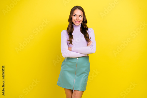 Portrait of pretty cheerful person crossed hands look interested empty space isolated on yellow color background