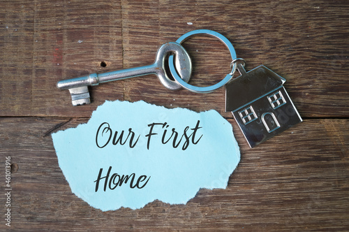 Key, toy house and torn paper written with text OUR FIRST HOME