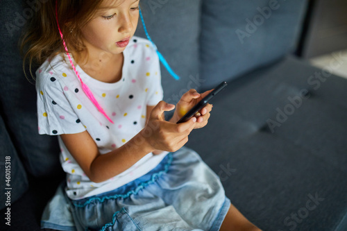 Child using cellphone on the sofa in modern and bright apartment