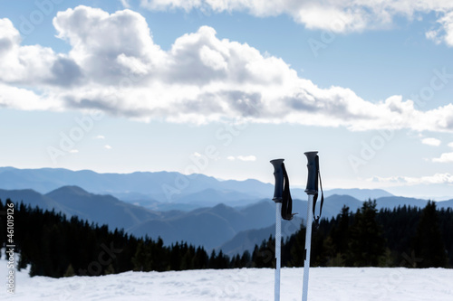 Downhill skiing, winter holidays and mountain resort vacations. Ski poles and background of wide snowy ski slope, silhouettes of mountains and blue sky. Pamporovo ski resort, Rhodopi, Bulgaria photo